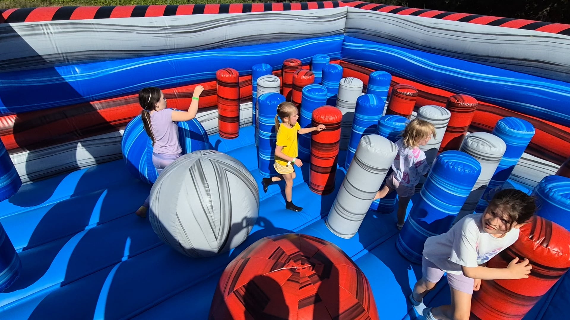 Blue-Red-Labyrinth Children play inside a colorful inflatable maze with blue, red, and gray pillars.