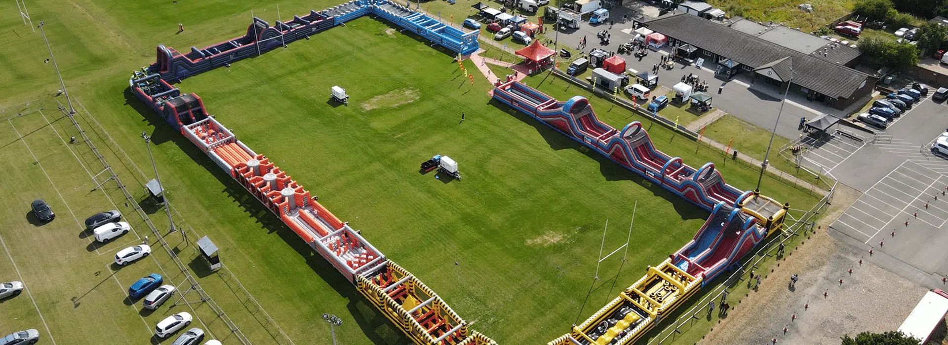 Aerial view of a large colorful inflatable obstacle course set up on a grassy field.