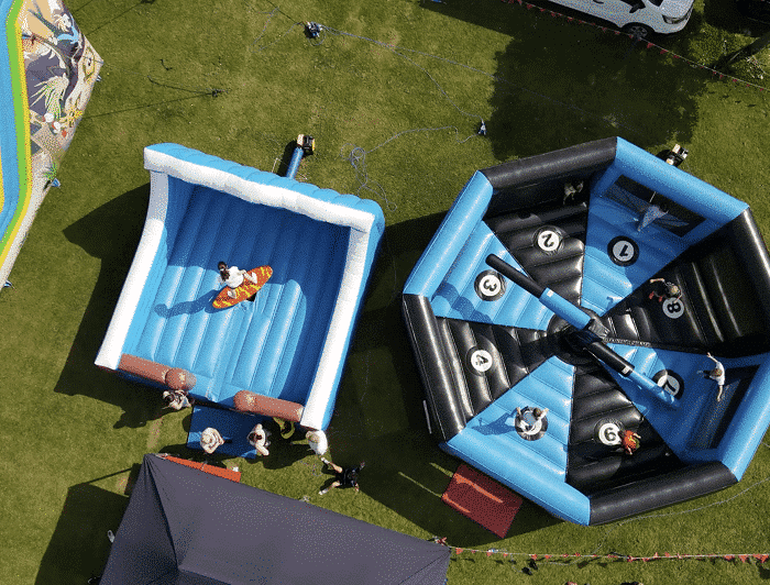 Aerial view of inflatable rides at an outdoor event, with people participating and watching.