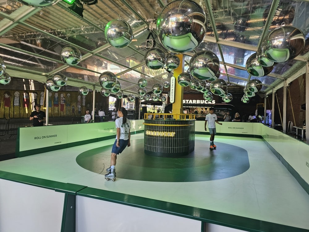 Roller skating rink with a Starbucks booth, disco balls, and people skating inside a covered venue.
