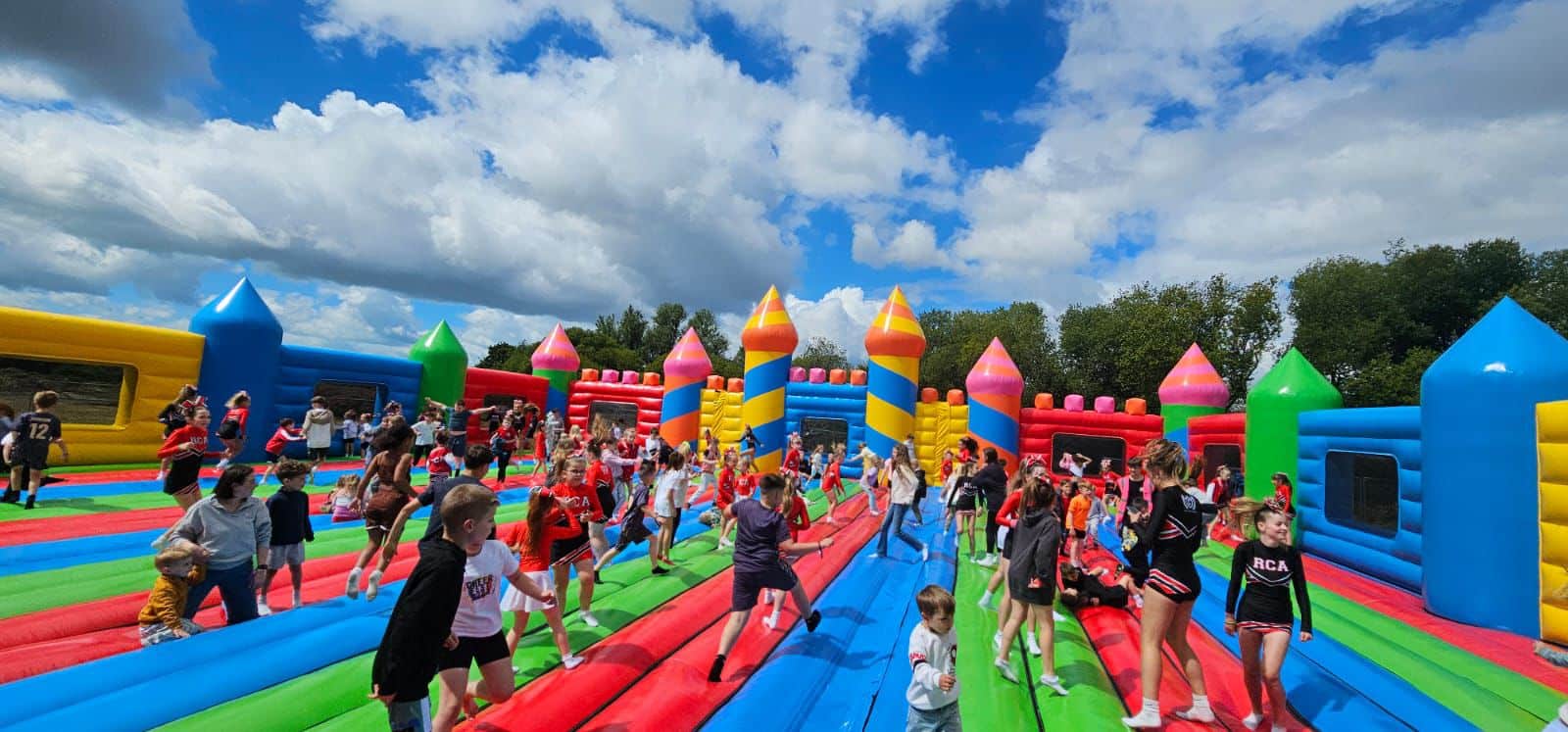 Aerial view of a large colorful inflatable obstacle course set up on a grassy field.