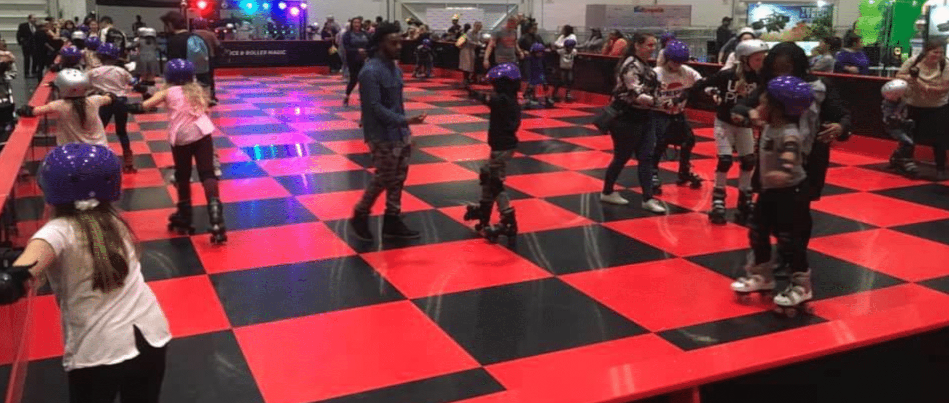 People roller skating in a colorful indoor rink with bright lights, palm trees, and large pink balloons.