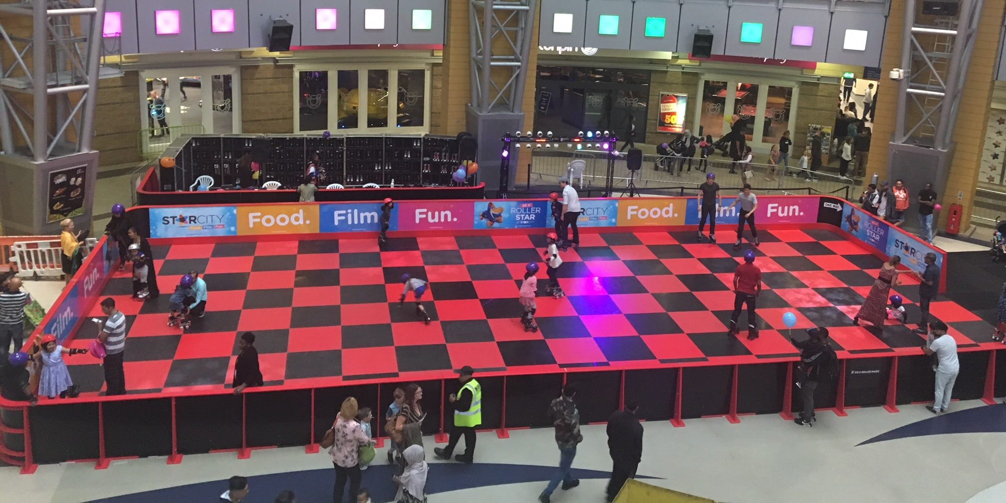 People roller skating under hanging disco balls in an indoor rink.