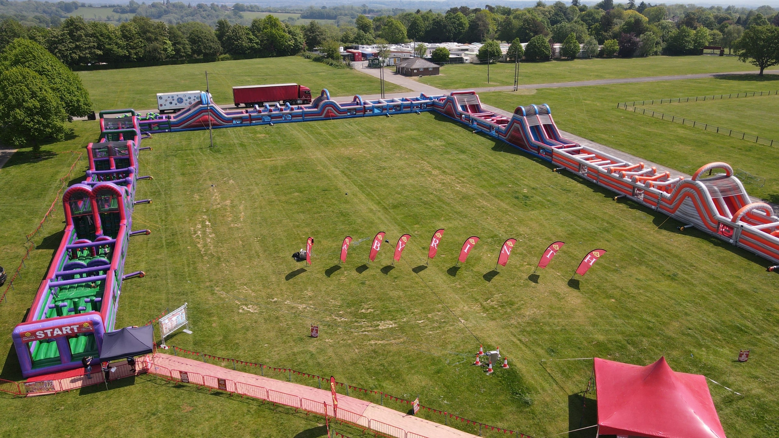 Lab Tour 195 Aerial view of a large colorful inflatable obstacle course set up on a grassy field.
