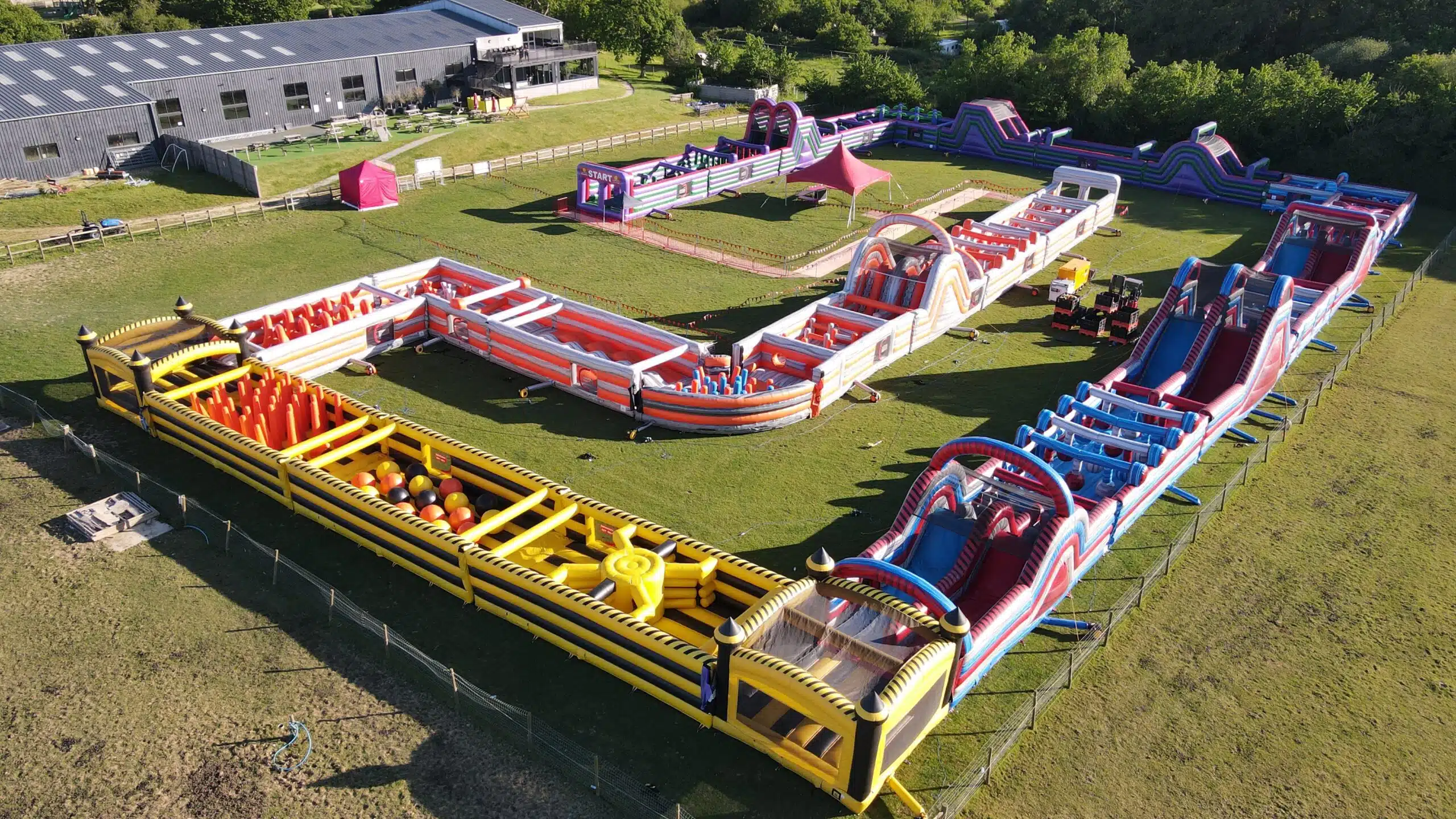 Two people play on an inflatable obstacle course with large hanging balls.