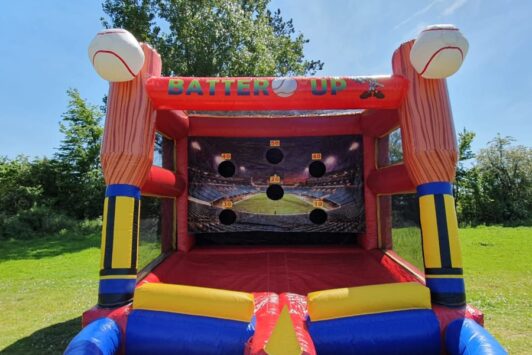 Inflatable baseball game with target holes outdoors on a sunny day.