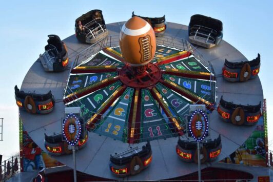 Colorful football-themed carnival ride with numbered seats and a large football at the center.