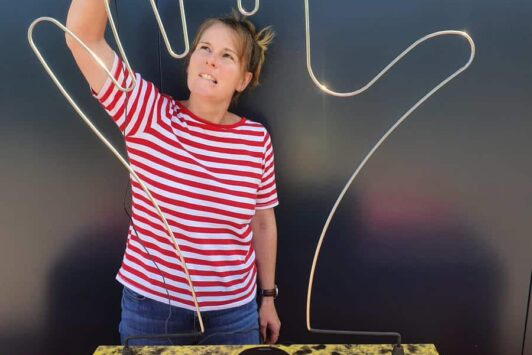 Woman playing a giant hand-shaped buzzer game, wearing a red and white striped shirt.