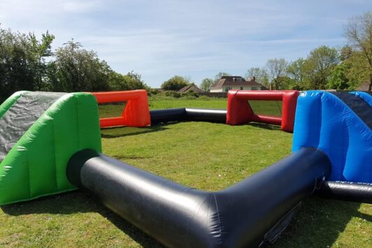 Inflatable football arena with four colorful goals on a grassy field.