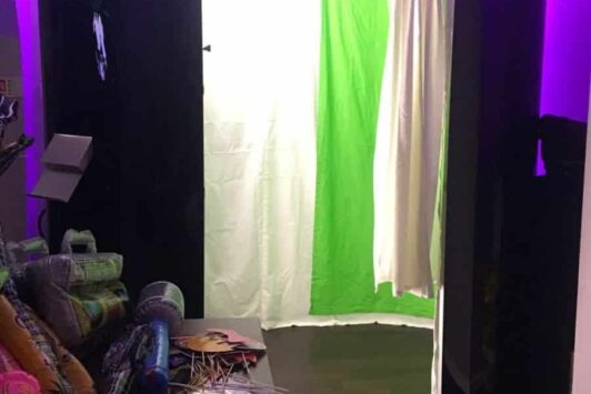 Photo booth with a green screen background and props on a table nearby.