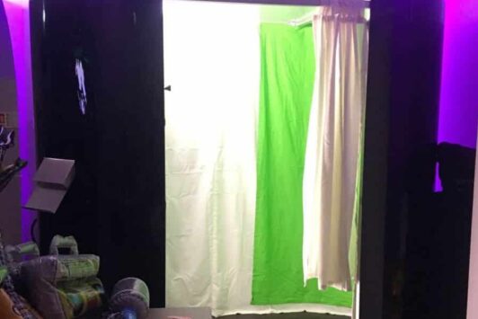 Photo booth with a green screen background and props on a table nearby.