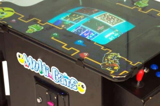 Tabletop arcade game machine with classic game graphics and control buttons.