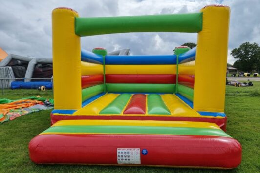 Colorful inflatable bouncy castle on grass under a cloudy sky.