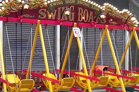 Children's fairground swingboats, brightly colored and empty, ready for riders.