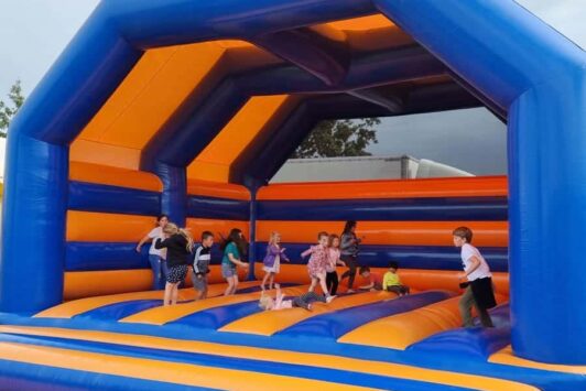 Children playing inside a large blue and orange bouncy castle.